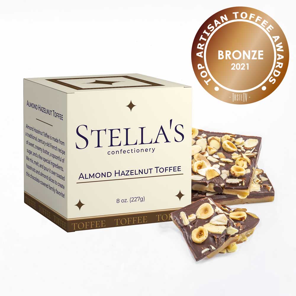 Box of Almond Hazelnut toffee next to toffee pieces and a bronze award badge