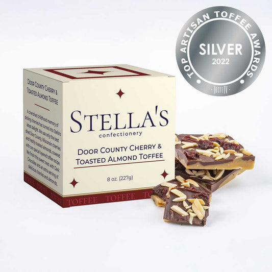 Box of Door County Cherry & Toasted Almond toffee next to toffee pieces and a silver award badge