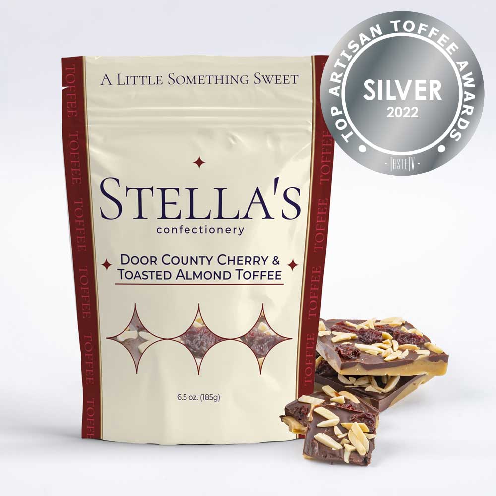 Stand up pouch of Door County Cherry & Toasted Almond toffee next to toffee pieces and a silver award badge